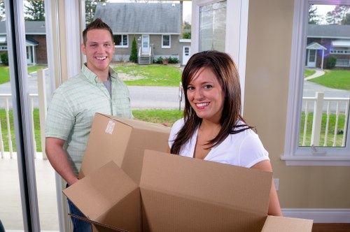 Professional movers carrying furniture through a stairwell in Bow
